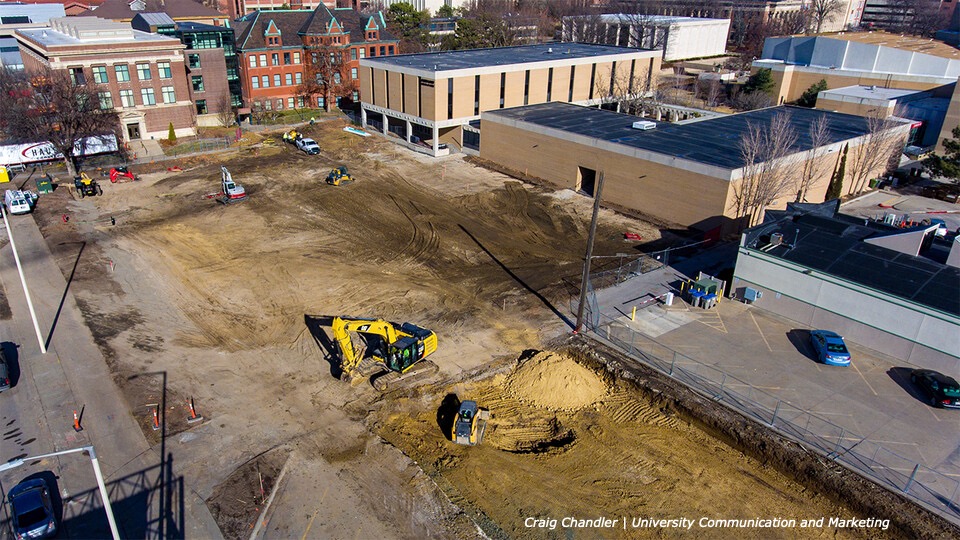 An excavator and bulldozer move earth at the corner of 10th and Q streets, where parking lots are being cleared to make way for the new Westbrook Music Building.